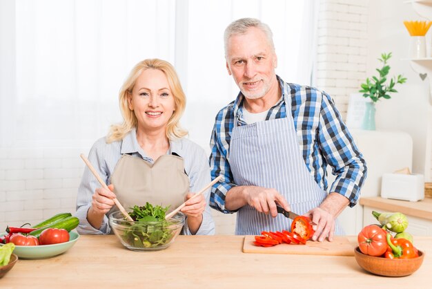 Portret van een hoger paar die het voedsel in de keuken voorbereiden