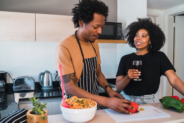 Portret van een jong afro paar samen koken in de keuken thuis. Relatie-, kook- en levensstijlconcept.