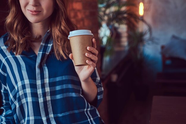 Portret van een jong hipstermeisje drinkt koffie in de ochtend, leunend op