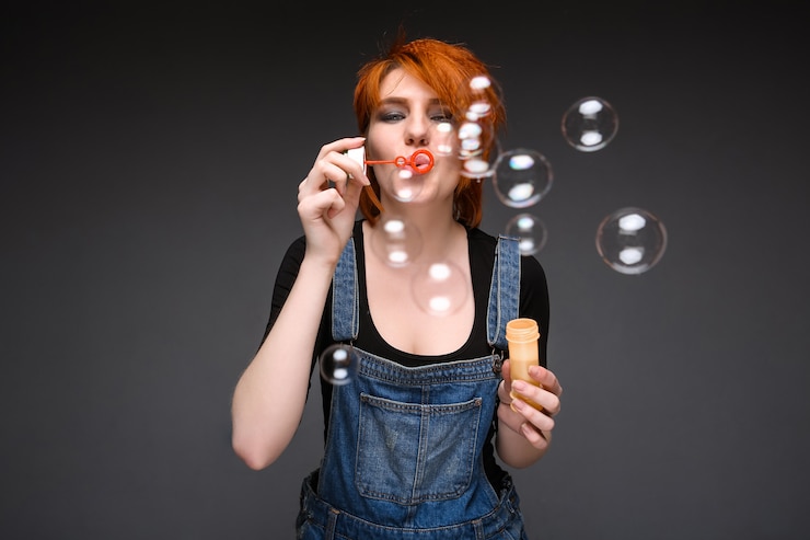 Gratis Foto portret van een jong meisje bellen blazen over grijze achtergrond.
