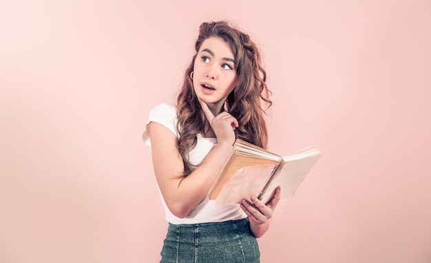 Portret van een jong meisje met een boek op een gekleurde muur