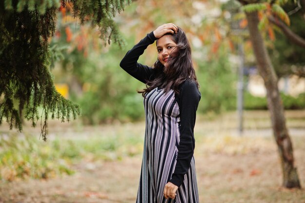 Portret van een jong, mooi Indiaas of Zuid-Aziatisch tienermeisje in een jurk in het herfstpark in Europa