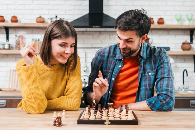 Portret van een jong paar dat het schaak in de keuken speelt