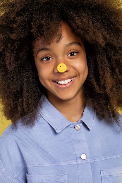 Gratis foto portret van een jong schattig meisje poseren met emoji-stickers op haar gezicht