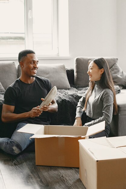 Portret van een jong stel met kartonnen dozen in een nieuw huis, een verhuisconcept