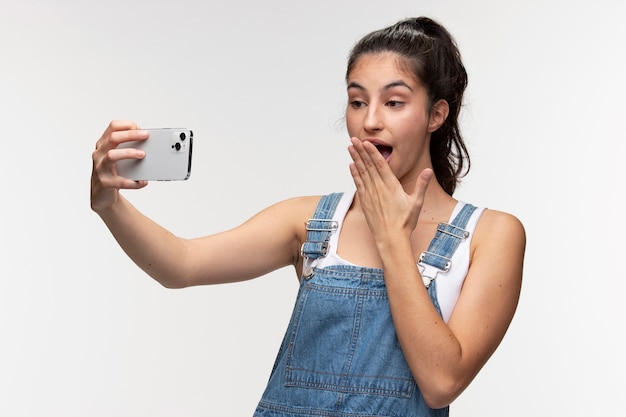 Portret van een jong tienermeisje in een overall die een selfie maakt met smartphone