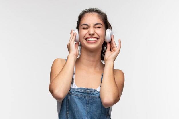 Portret van een jong tienermeisje in een overall die naar muziek luistert op een koptelefoon