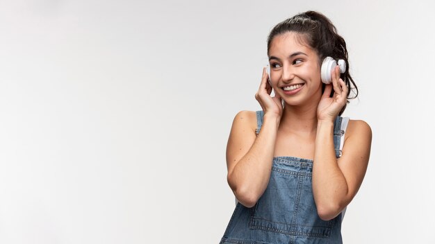 Portret van een jong tienermeisje in een overall die naar muziek luistert op een koptelefoon