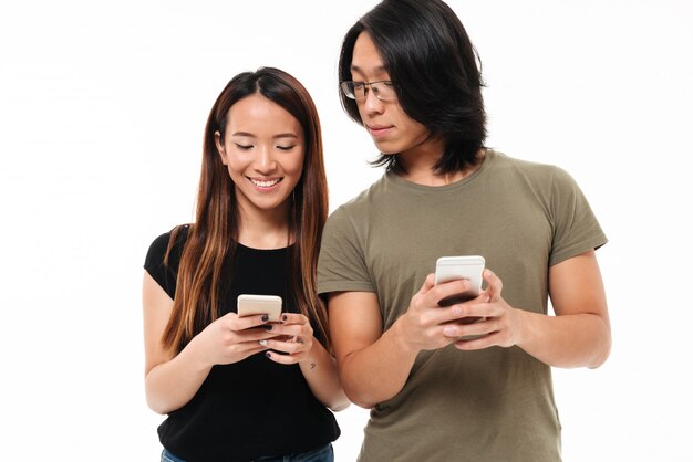 Portret van een jong toevallig Aziatisch paar dat mobiele telefoons met behulp van