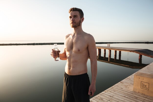 Portret van een jong vermoeid sportman drinkwater na het joggen