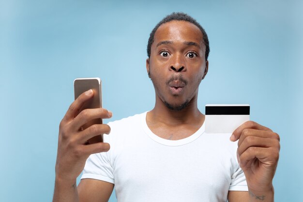 portret van een jonge Afro-Amerikaanse man in wit overhemd met een kaart en smartphone.