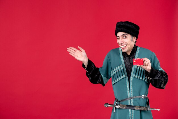Portret van een jonge Azerbeidzjaanse man in traditionele klederdracht met creditcard op rood