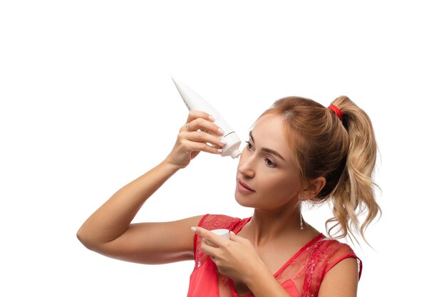 Portret van een jonge blanke vrouw met halflang blond haar is gevlochten in een paardenstaart, met een mooie heldere huid, doe een anti-rimpelprocedure met speciale crème