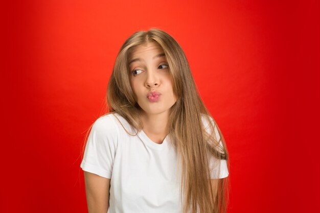 Portret van een jonge blanke vrouw met heldere emoties op een felrode muur