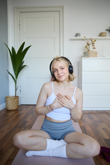 Gratis foto portret van een jonge blonde vrouw met koptelefoon die zich kalm en ontspannen voelt na meditatie-yoga-training