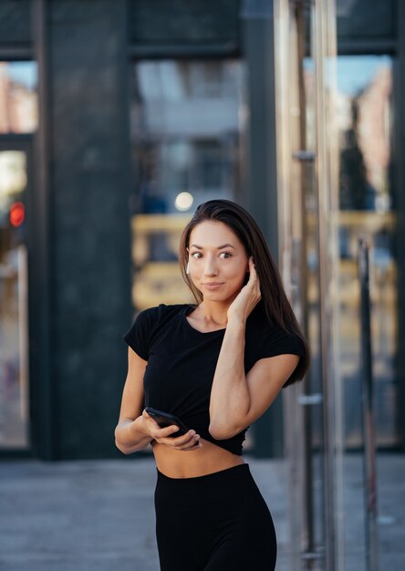 Portret van een jonge brunette vrouw met koptelefoon en lachend tijdens het wandelen