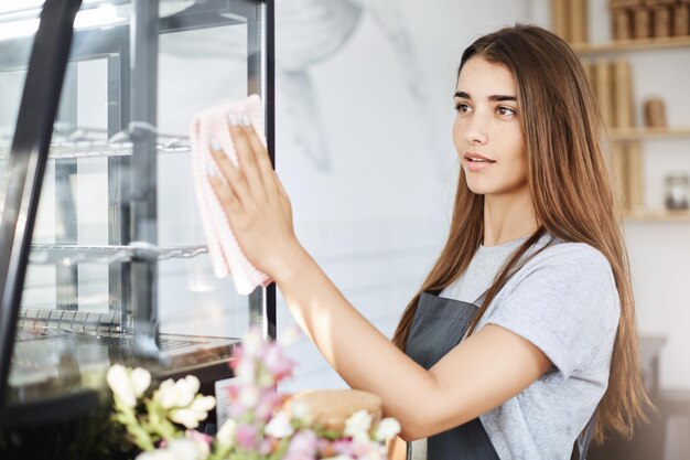 Portret van een jonge café-eigenaar die veeg gebruikt om alles schoon te maken voordat het wordt geopend