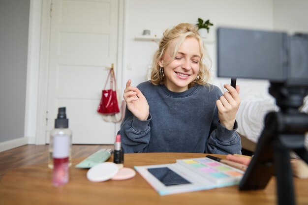 Portret van een jonge contentmaker vrouwelijke blogger die een video opneemt met een digitale camera met lippenstift