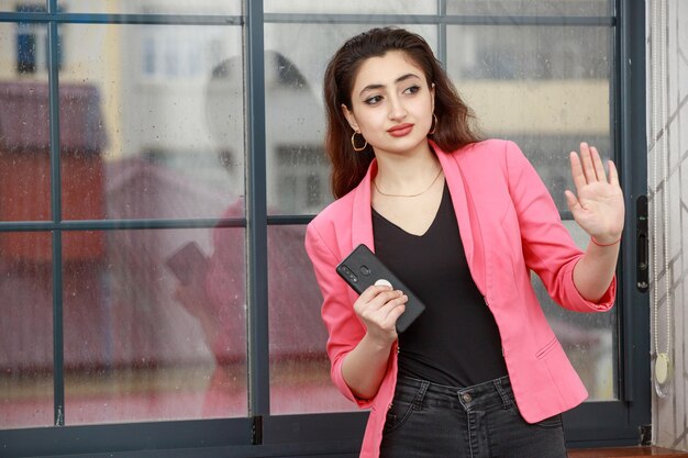 Portret van een jonge dame die haar telefoon vasthoudt en haar hand schudt