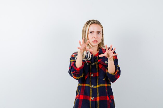 Portret van een jonge dame die handen op agressieve manier in geruit overhemd houdt en ernstig vooraanzicht kijkt