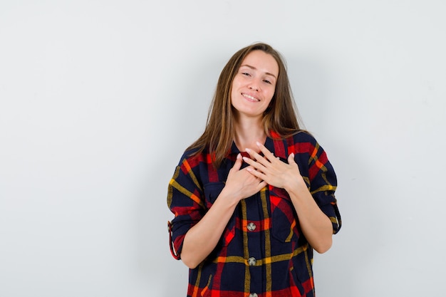 Portret van een jonge dame die handen op de borst in casual shirt houdt en dankbaar vooraanzicht kijkt