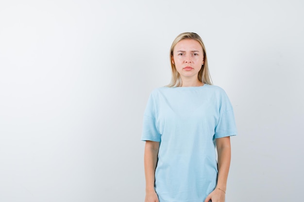 Portret van een jonge dame die naar de camera in een t-shirt kijkt en weemoedig kijkt