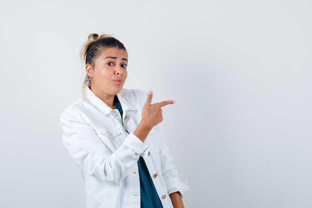 Portret van een jonge dame die rechts in een witte jas wijst en zich afvraagt vooraanzicht