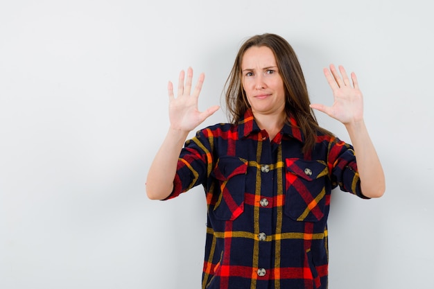 Gratis foto portret van een jonge dame die stopgebaar in casual shirt toont en resoluut vooraanzicht kijkt