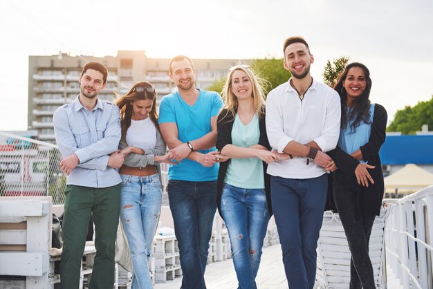 Portret van een jonge en gelukkige mensen in rust op de pier. Vrienden die genieten van een spel op het meer. Positieve emoties.