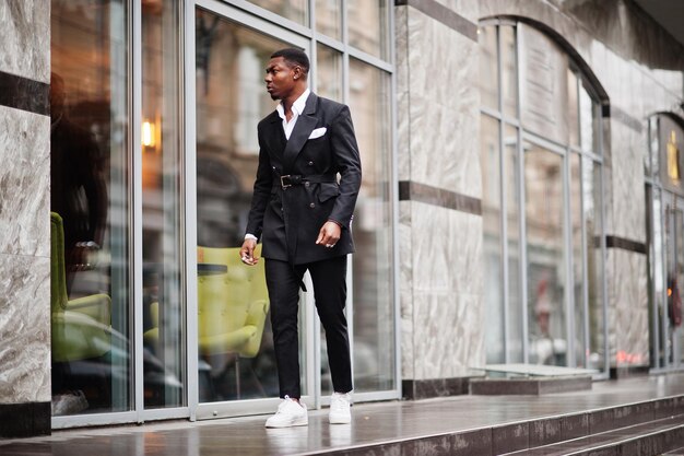 Portret van een jonge en knappe Afro-Amerikaanse zakenman in pak en witte sneakers