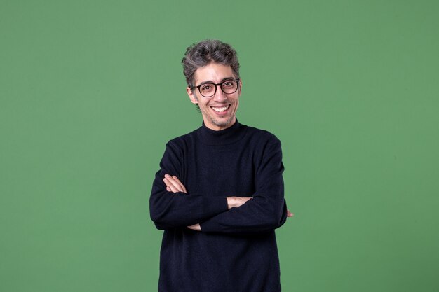 Portret van een jonge geniale man, nonchalant gekleed en tevreden in studio-opname op groene muur