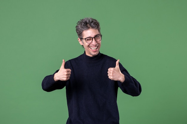 Portret van een jonge geniale man, nonchalant gekleed in een studio die gelukkig en tevreden is geschoten op de groene muur