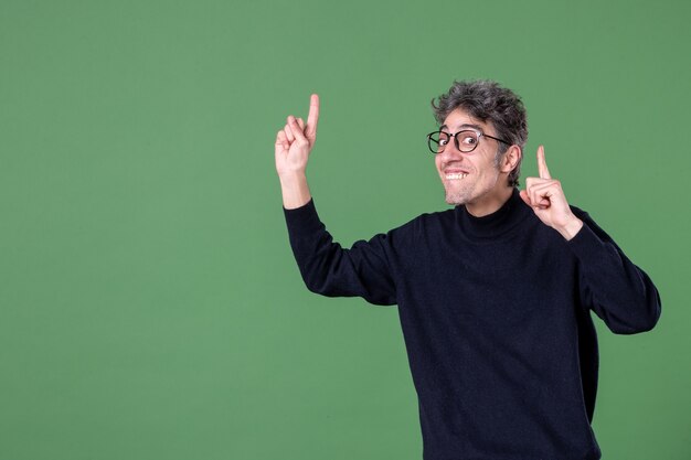 Portret van een jonge geniale man, nonchalant gekleed in een studio-opname die tevreden is op de groene muur