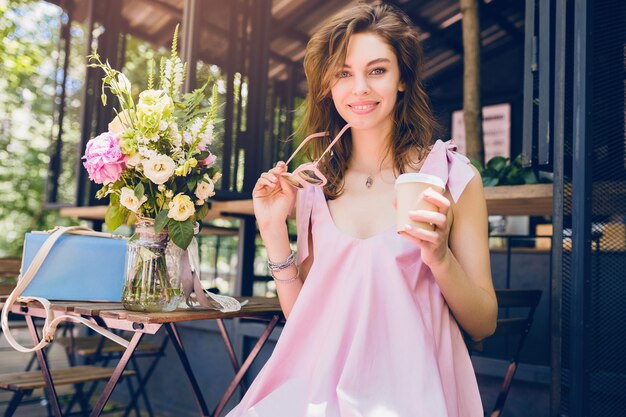 Portret van een jonge glimlachende gelukkige mooie vrouw die in café koffie drinkt