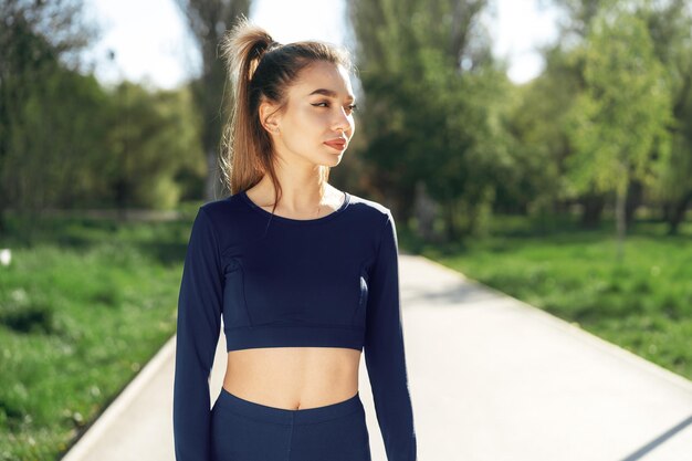 Gratis foto portret van een jonge glimlachende vrouw die sportkleding draagt in het ochtendpark