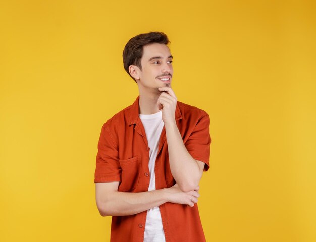 Portret van een jonge knappe man die zelfverzekerd naar de camera kijkt met een glimlach met gekruiste armen en hand op de kin over geïsoleerde achtergrond