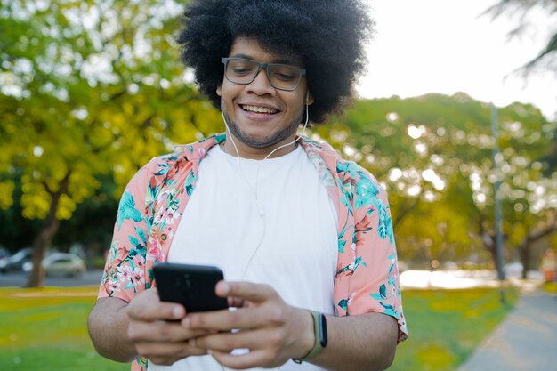 Portret van een jonge latijns-man die zijn mobiele telefoon gebruikt terwijl hij buiten op straat staat. stedelijk concept