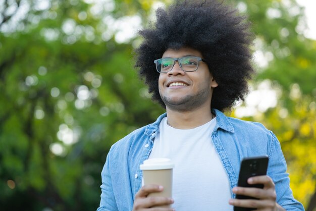 Portret van een jonge Latijns-man met behulp van zijn mobiele telefoon terwijl hij buiten op straat staat. Stedelijk concept.