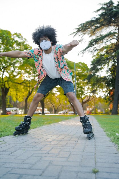 Portret van een jonge Latijns-man met een gezichtsmasker terwijl hij buiten op straat rolschaatst