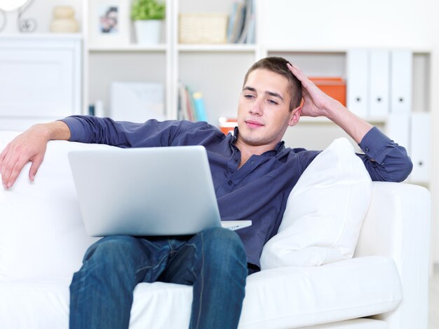 Portret van een jonge man aan het werk op de laptop thuis