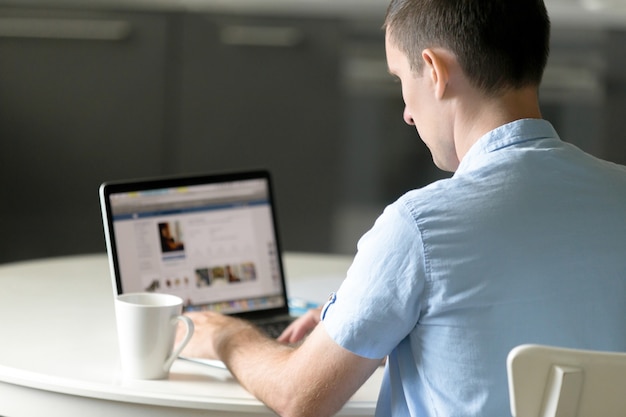 Portret van een jonge man die aan bureau werkt met laptop