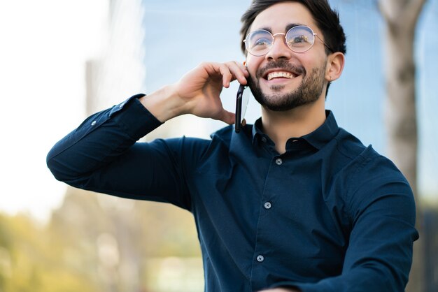 Portret van een jonge man die aan de telefoon praat terwijl hij buiten staat