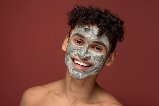 Portret van een jonge man die lacht met een gezichtsmasker op