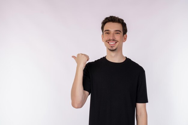 Portret van een jonge man die met de vingers wijst naar kopieerruimte geïsoleerd op een witte studioachtergrond