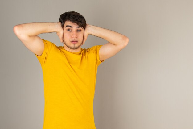 Portret van een jonge man die staat en naar de camera kijkt tegen grijs.