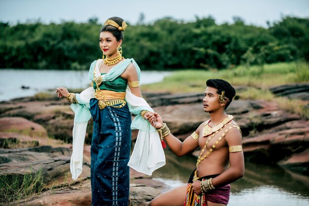 Portret van een jonge man en vrouw met een prachtig traditioneel kostuum poseren in de natuur in Thailand