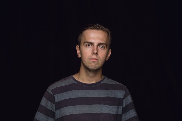 Portret van een jonge man geïsoleerd op zwarte muur close-up