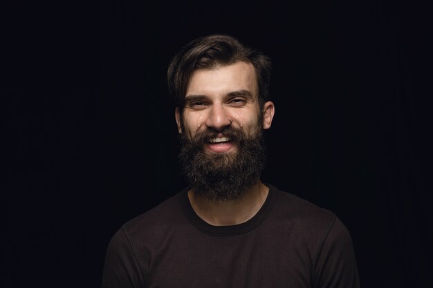 Portret van een jonge man geïsoleerd op zwarte studio achtergrond close-up. Photoshot van echte emoties van mannelijk model. Huilend door lachen en lachen. Gelaatsuitdrukking, concept van menselijke emoties.