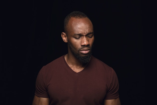 Portret van een jonge man geïsoleerd op zwarte studio muur close-up