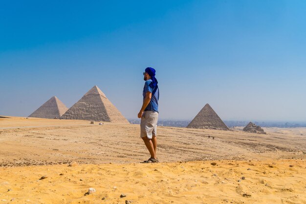 Portret van een jonge man in een blauwe tulband die naast de piramides van Gizeh, Caïro, Egypte loopt